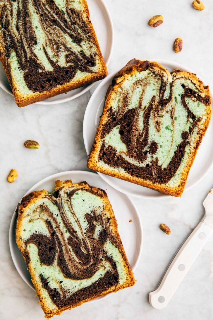 photo showing three slices of chocolate pistachio loaf cake on small white plates