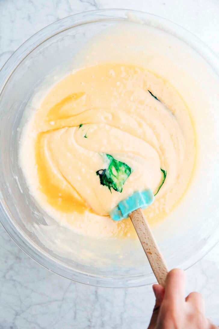 photo of michelle mixing pistachio extract and green food coloring into the batter