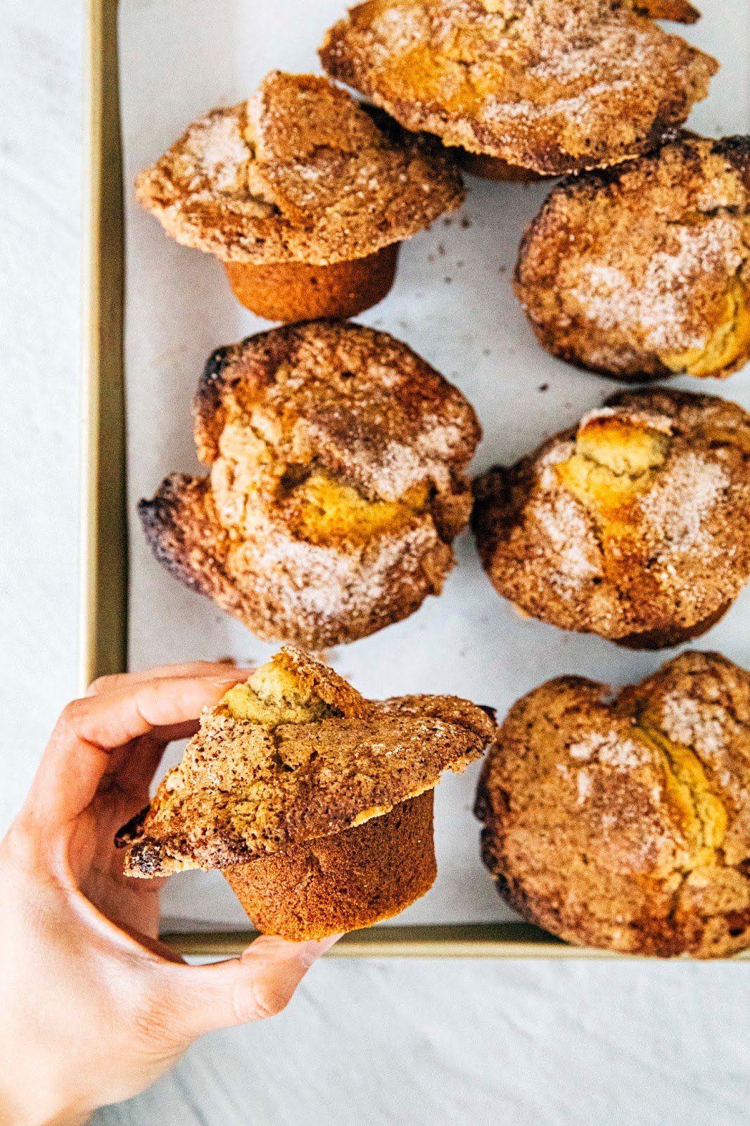 photo of hand holding a banana cinnamon muffin showing off its domed top